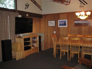 A living room with a TV, wooden furniture, and framed pictures on the wall.