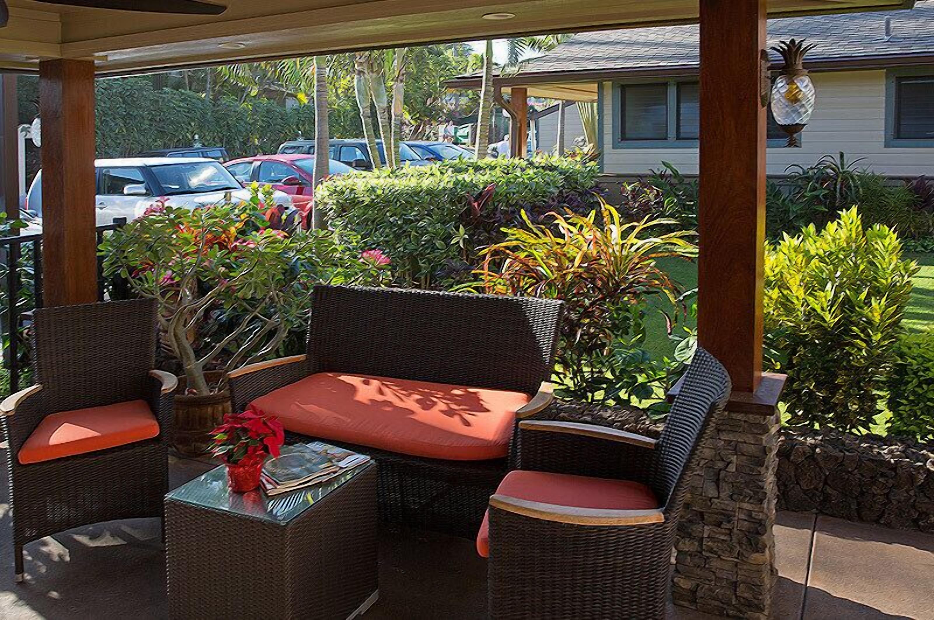 An outdoor patio with wicker furniture, a small table, and a potted plant.