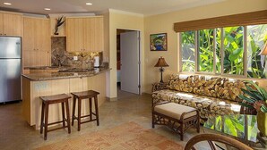 A kitchen with wooden cabinets, a granite countertop, and a built-in island with stools. - Hale Napili (Lahaina)