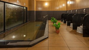 A modern bathroom with a glass-enclosed shower, wooden walls, and multiple toilet stalls. - Hotel Route Inn Minami Yokkaichi (Yokkaichi)