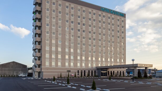 A multi-story hotel with a flat facade, numerous windows, and a sign reading "HOTEL ROUTINE IN". - Hotel Route Inn Minami Yokkaichi (Yokkaichi)