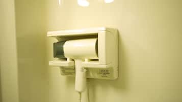 Un secador de pelo fijado a la pared con cable.