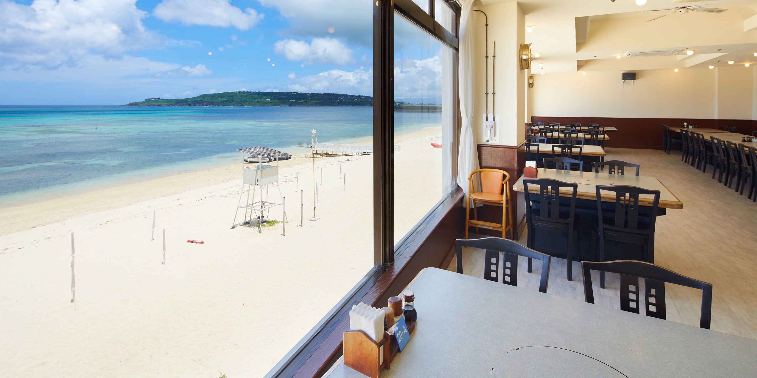 Un restaurant situé en bord de mer, offrant une vue sur l’océan et une île au loin.