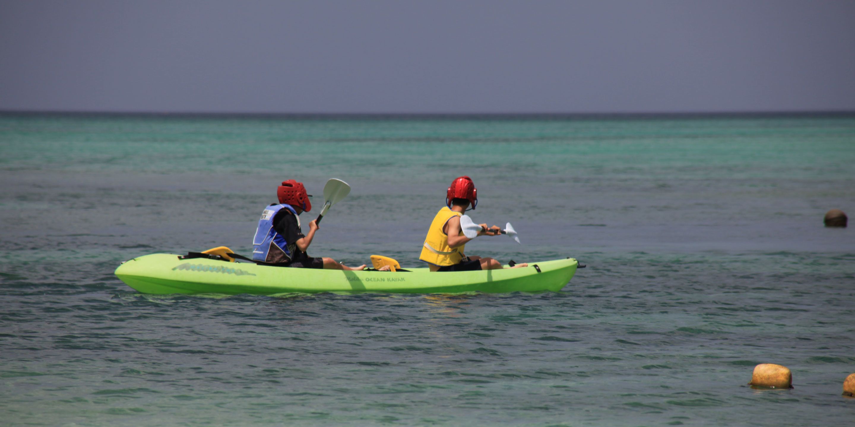 Two people kayaking on a calm sea.