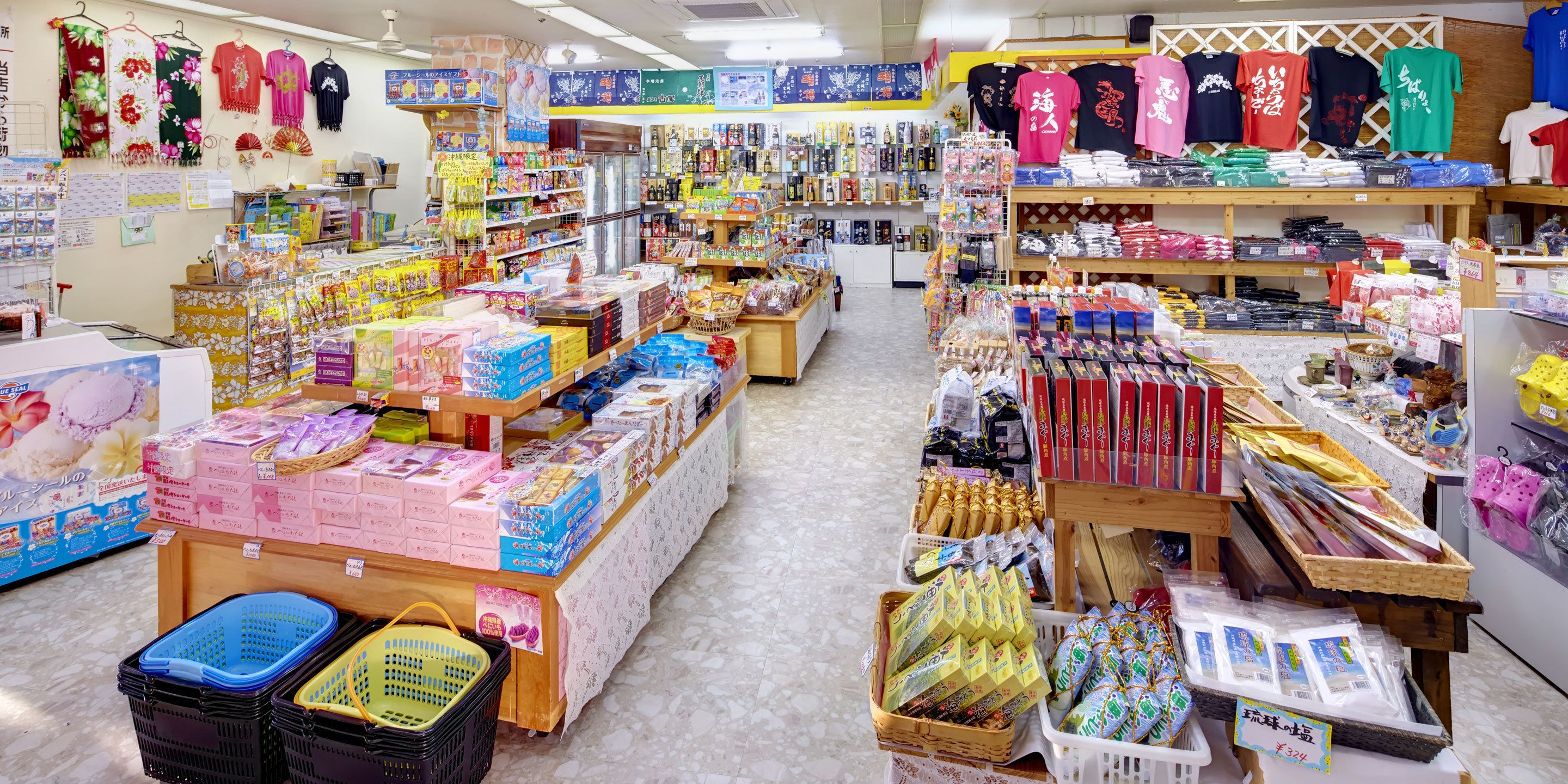 Un magasin bien organisé, avec une variété de produits exposés sur des étagères et des tables, notamment des collations, des boissons et des articles ménagers.