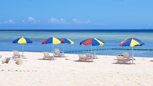 Una playa con cuatro sombrillas y varias sillas de playa.
