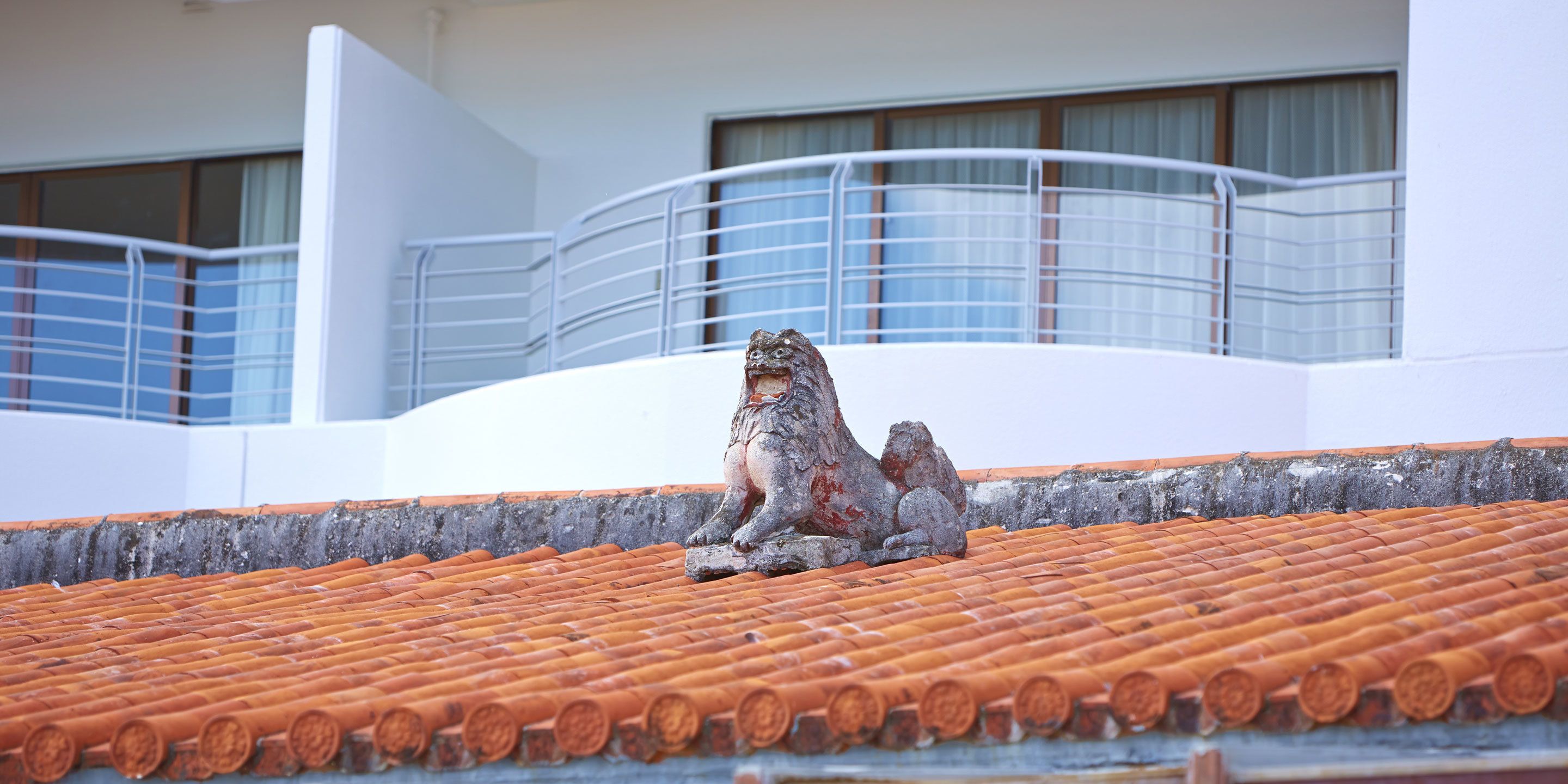 A rooftop with a traditional tiled roof and a stone lion statue.