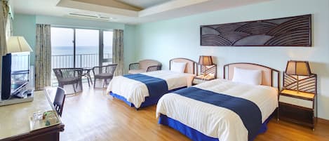 A hotel room with two beds, a desk, a chair, a view of the ocean, and a decorative wall piece.