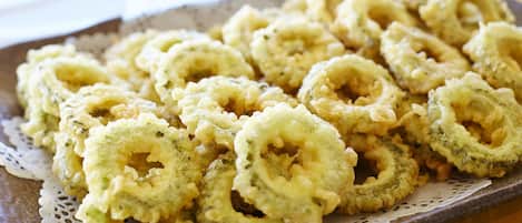 A tray of fried calamari rings on a ceramic plate with a lace doily underneath.