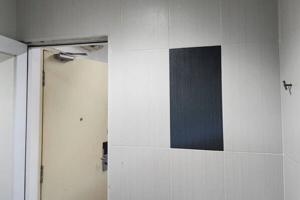 Un baño con puerta, paredes de azulejos y un interruptor de luz a la vista.