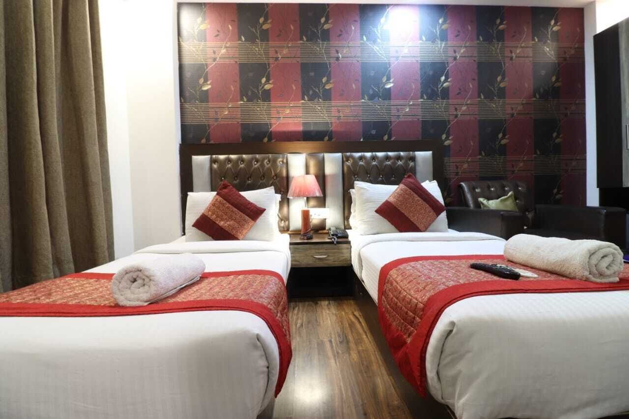 A hotel room with two beds, each with a red and white bedspread, a headboard, and a nightstand with a lamp.