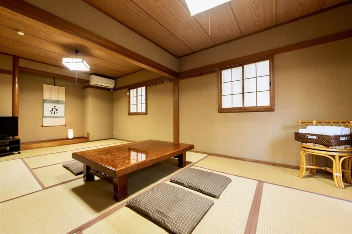 Una habitación japonesa tradicional con suelo de tatami, una mesa de madera baja, un televisor y un futón.