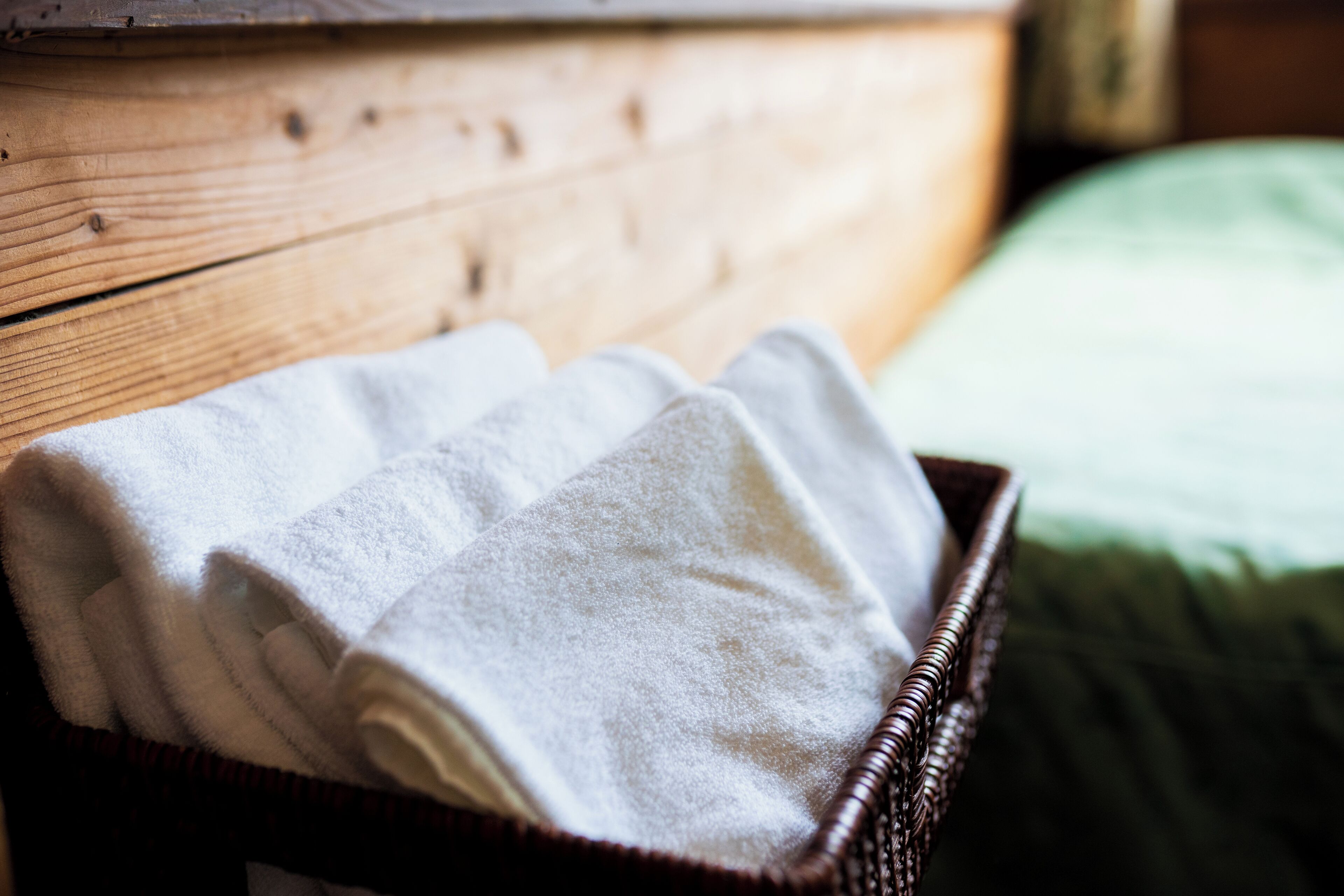 A wicker basket with folded towels on a wooden surface.