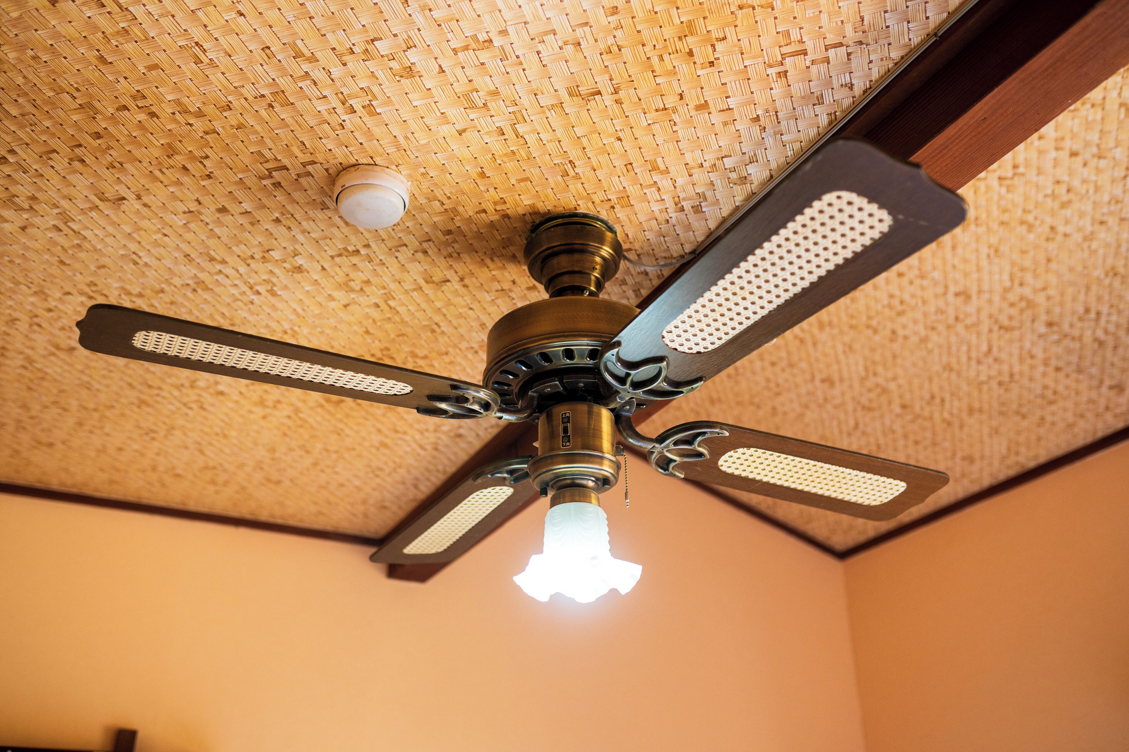 A ceiling fan with a light fixture in a room with a textured ceiling.