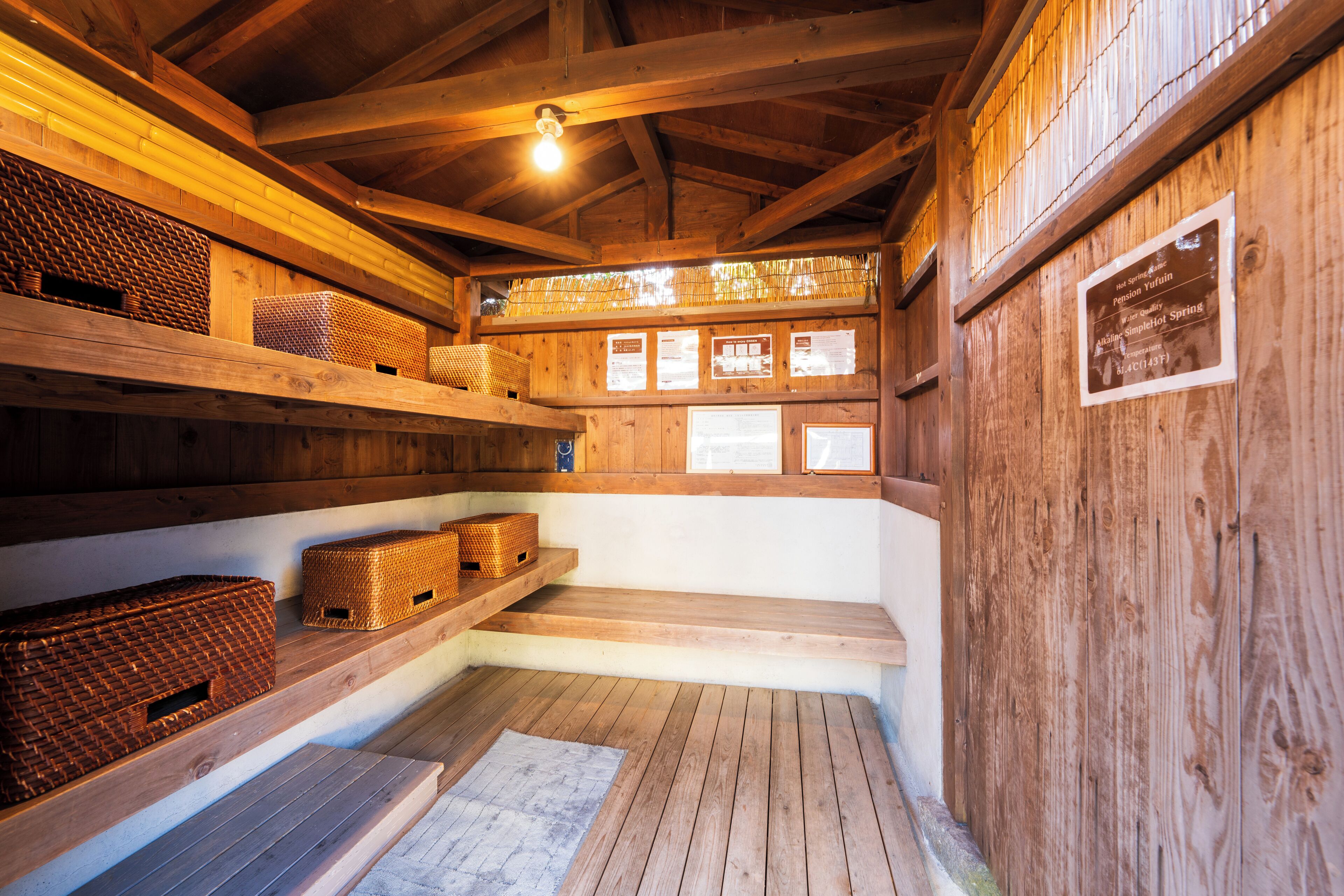 A wooden interior with shelves holding baskets, a wooden bench, and a sign on the wall.