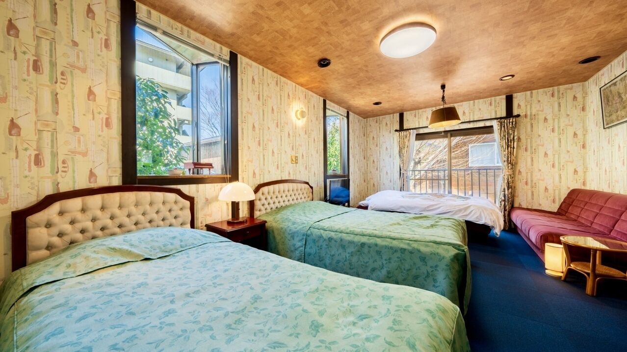 Una habitación con dos camas, un sofá, una mesa y una ventana con vistas.
