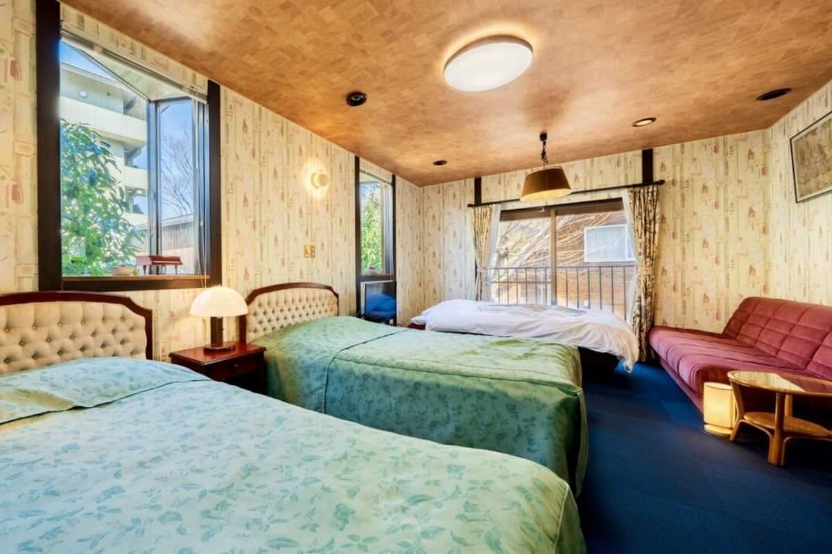 Una habitación con dos camas, un sofá, una mesa y una ventana con vistas.