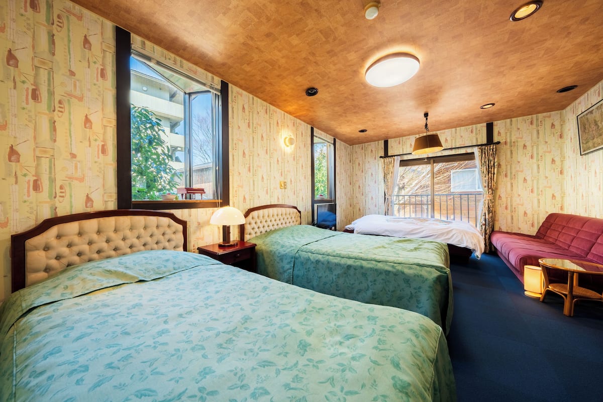 Una habitación con dos camas, un sofá y una mesita.
