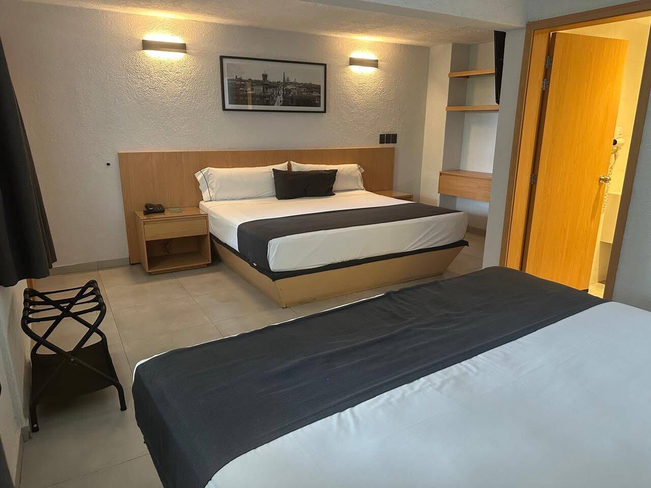 A hotel room with a bed, bedside table, and a chair.