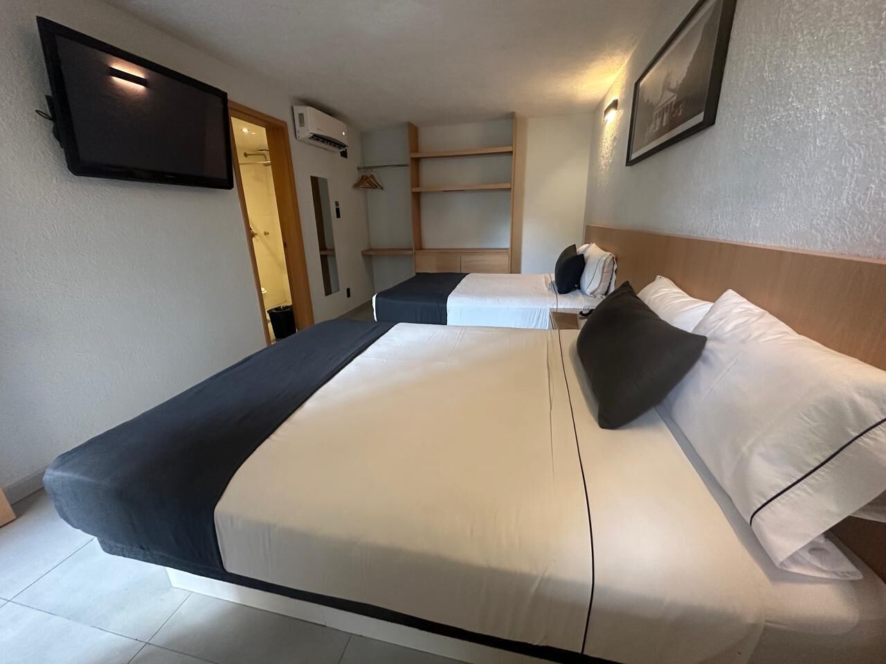 Habitación de hotel con una cama grande, un televisor en la pared y un armario.