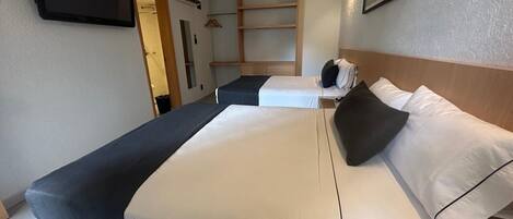 Habitación de hotel con una cama grande, un televisor en la pared y un armario.