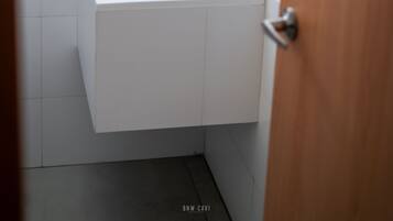 Une salle de bain avec un lavabo blanc, un sèche-cheveux et un miroir.