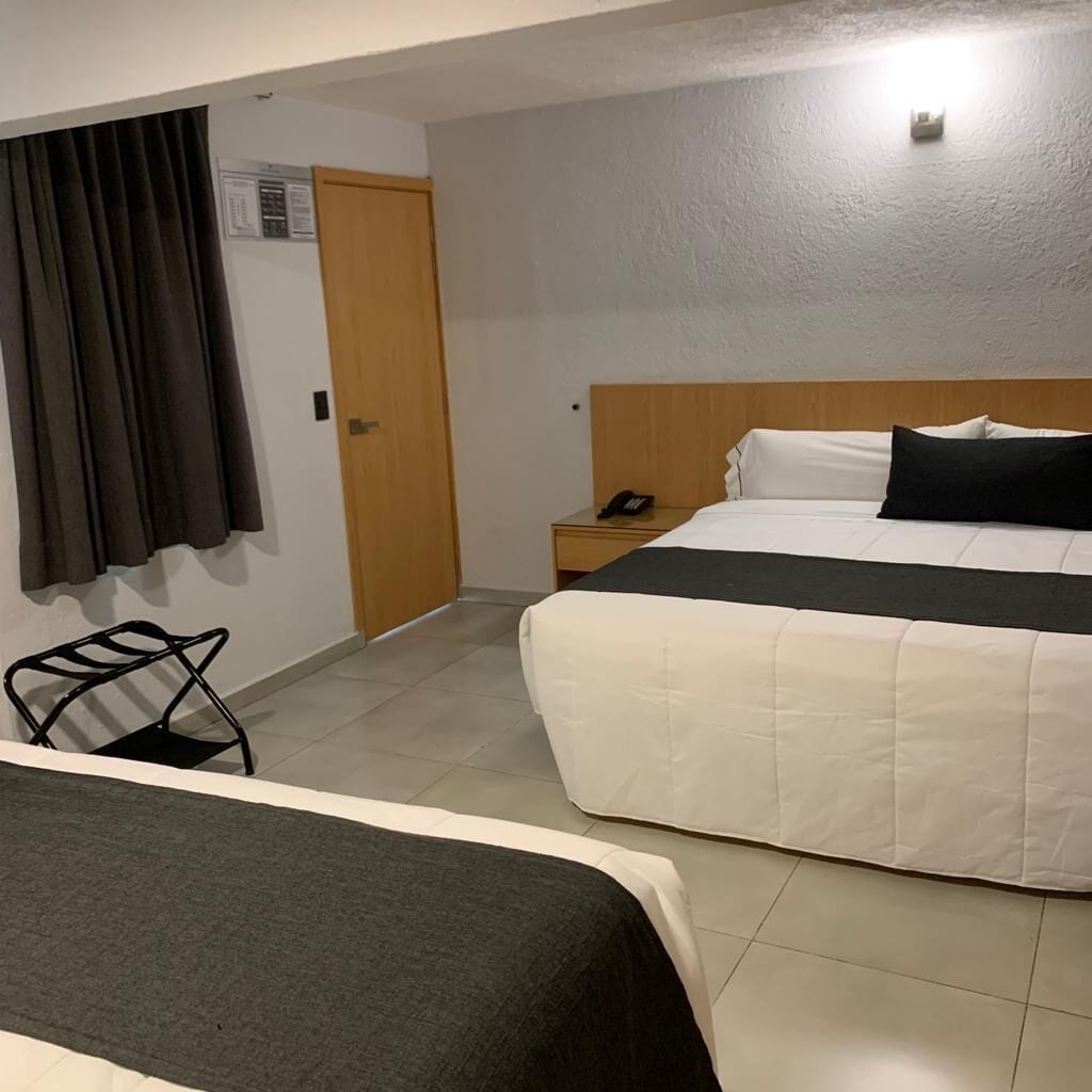 Une chambre d’hôtel avec un lit, une table de chevet, une chaise et une fenêtre avec des rideaux.