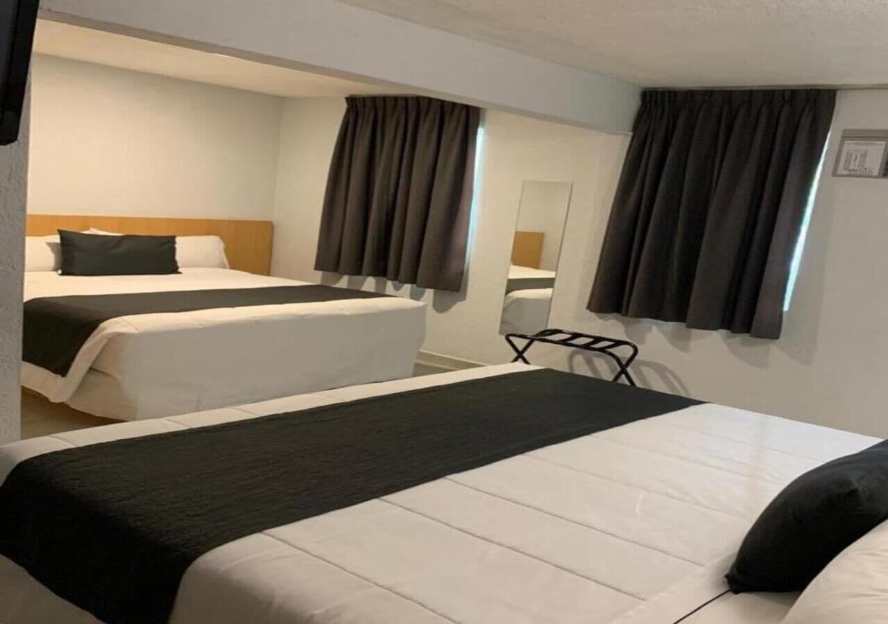 A hotel room with two beds, a desk, and a chair.