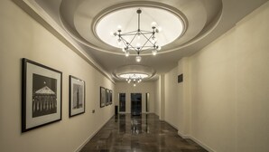 A hallway with a polished marble floor, framed black-and-white photographs on the walls, and a modern chandelier with multiple bulbs. - Hotel Emperador Centro Guadalajara y Remodelado (Guadalajara)