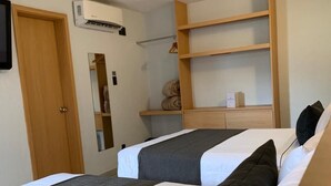 A room with two beds, a wooden wardrobe, a mirror, and a shelf with folded towels. - Hotel Emperador Centro Guadalajara y Remodelado (Guadalajara)