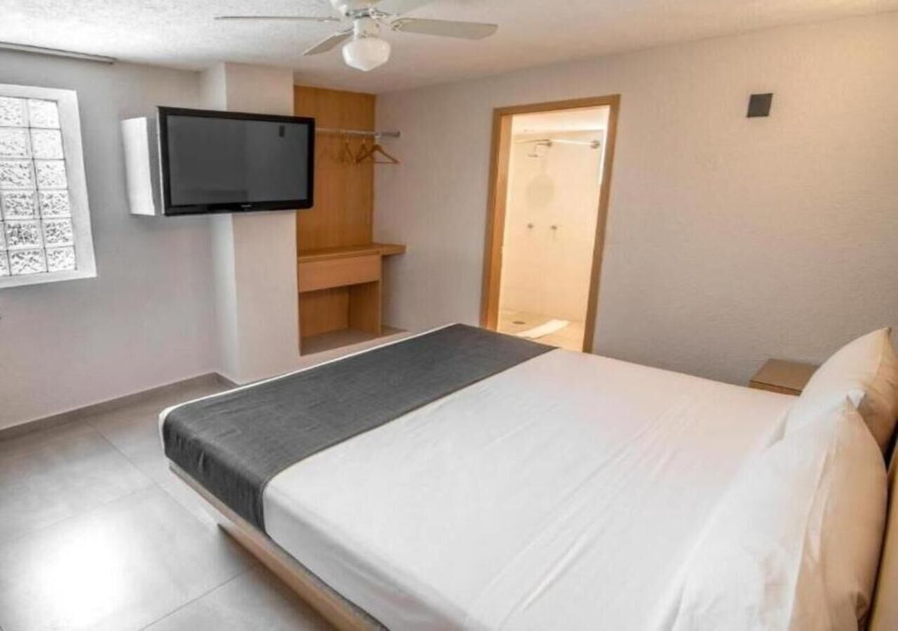 A bedroom with a bed, a television, a wardrobe, and a ceiling fan.
