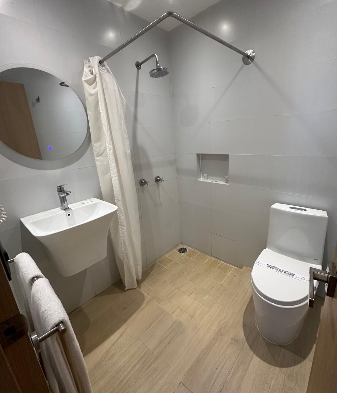 A modern bathroom with a shower, toilet, sink, and a mirror.