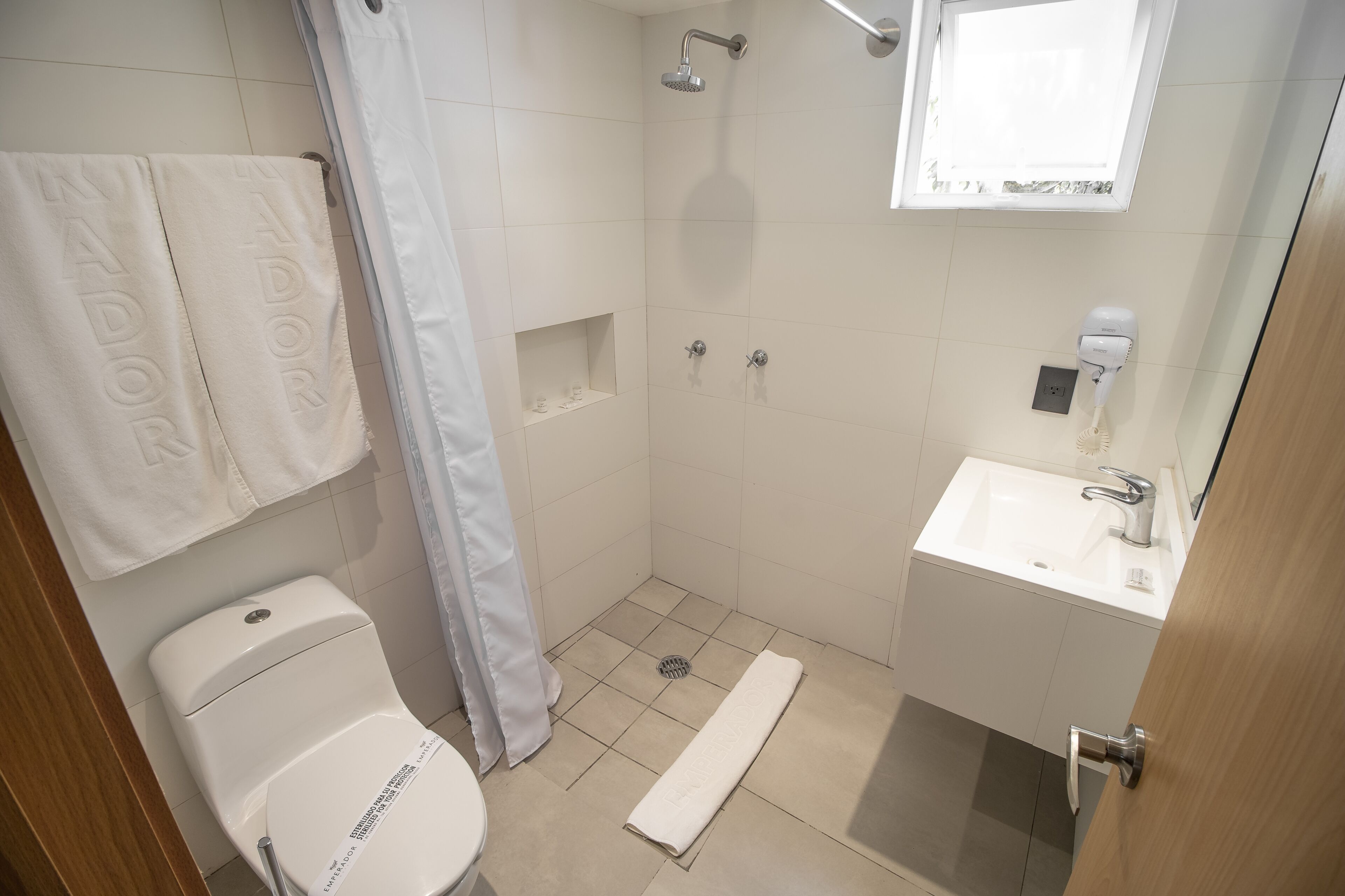 A bathroom with a toilet, shower, and sink.