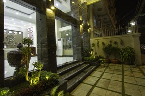 Ein Hotel Eingangsbereich mit einer Rezeption, einem großen dekorativen Brunnen und Stufen zum Eingang.