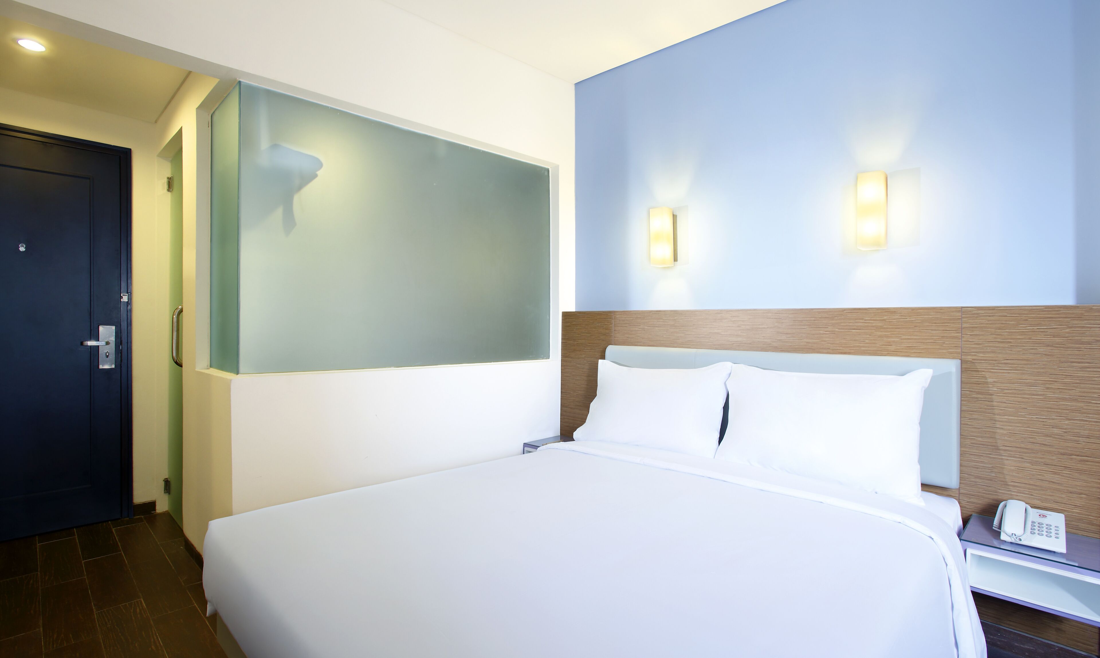 A hotel room with a large bed, a bedside telephone, and a nightstand.