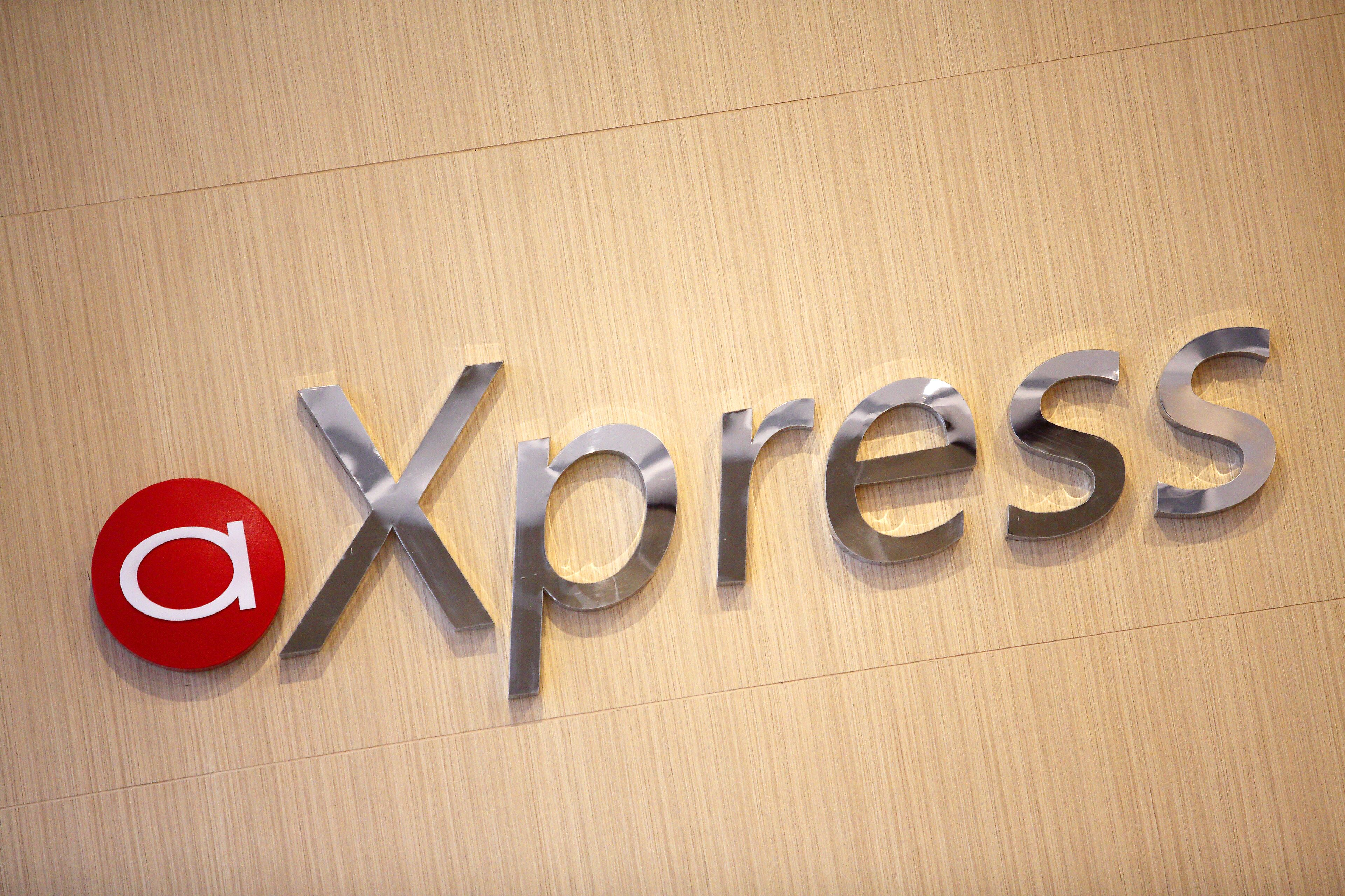 A logo with the letter 'a' in red and the word 'Xpress' in metallic letters on a wooden background.