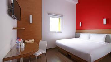 Une chambre d’hôtel avec un lit, un bureau, une chaise, une télévision et une fenêtre.