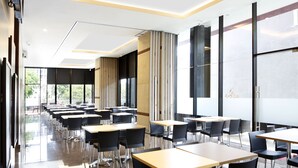Zona pranzo moderna con tavoli e sedie, ampie finestre e un design pulito e minimalista.