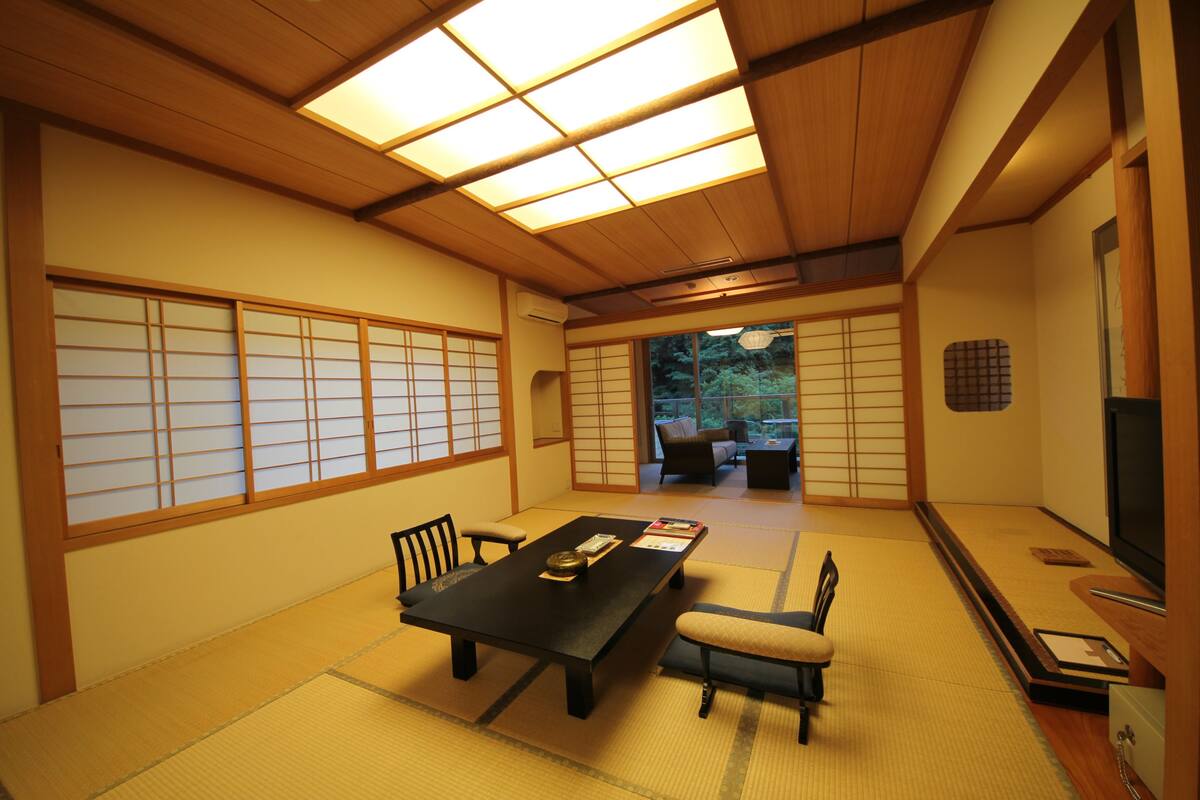 A traditional Japanese room with tatami flooring, a low table, and sliding doors.