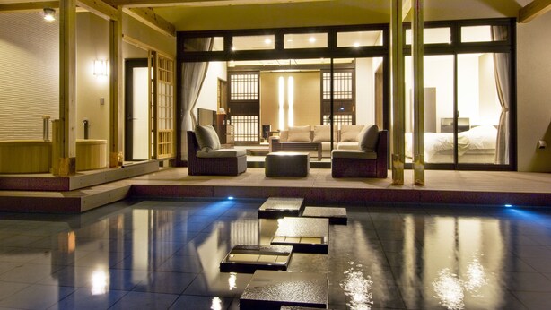 Una habitación tradicional japonesa con suelo de tatami, una mesa baja y un sofá.