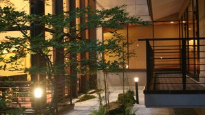 Un edificio moderno con amplios ventanales, una escalera y un jardín con helechos.