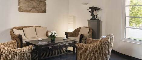 A room with wicker furniture, a globe artwork, a statue, and a window with a view.
