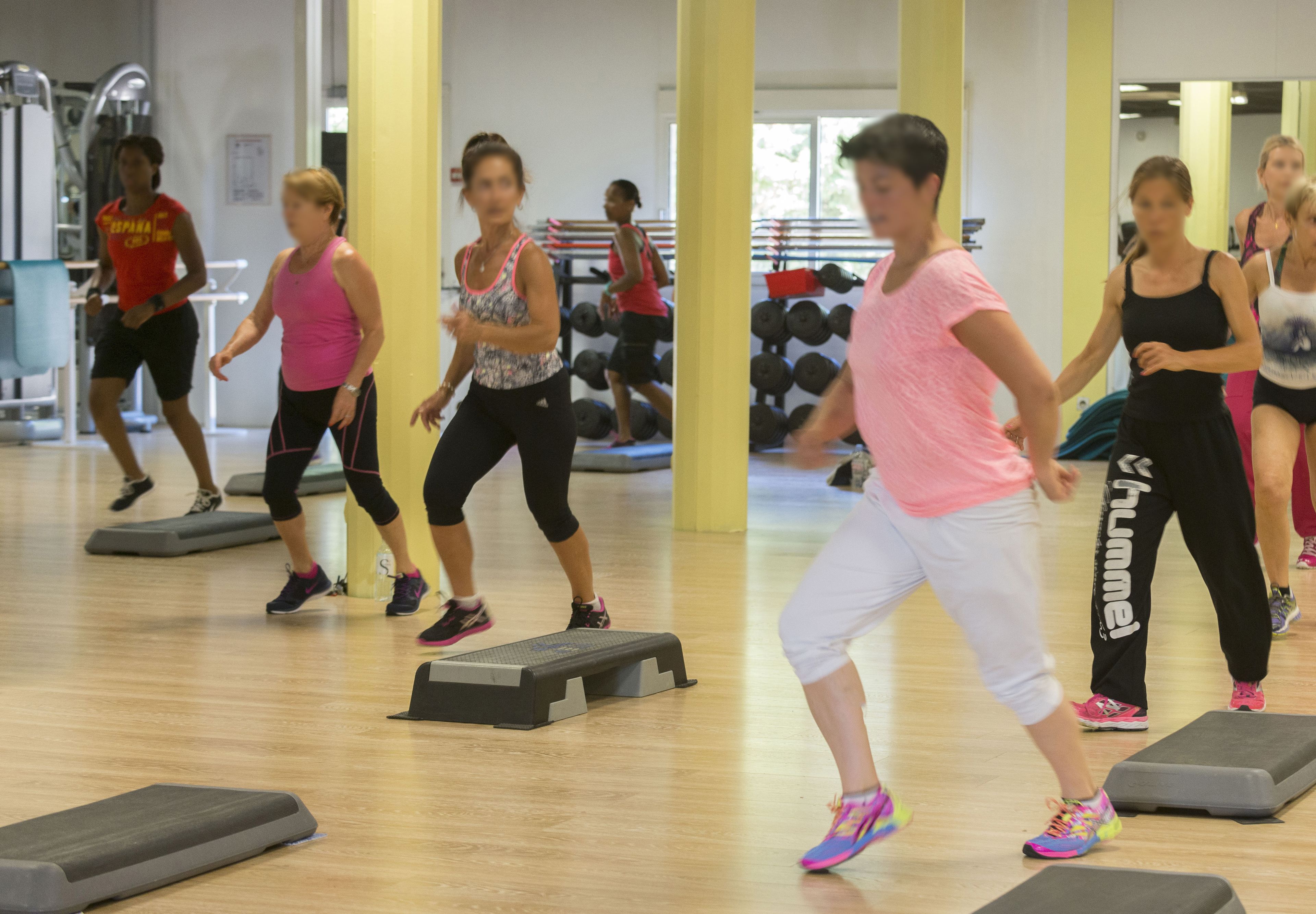 Eine Gruppe von Menschen trainiert in einem Fitnessstudio mit Laufbändern und Gewichten.