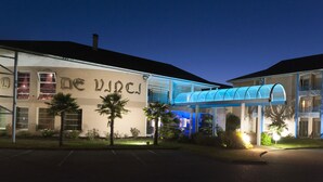 A hotel with a modern design, featuring a covered walkway and palm trees in the front.