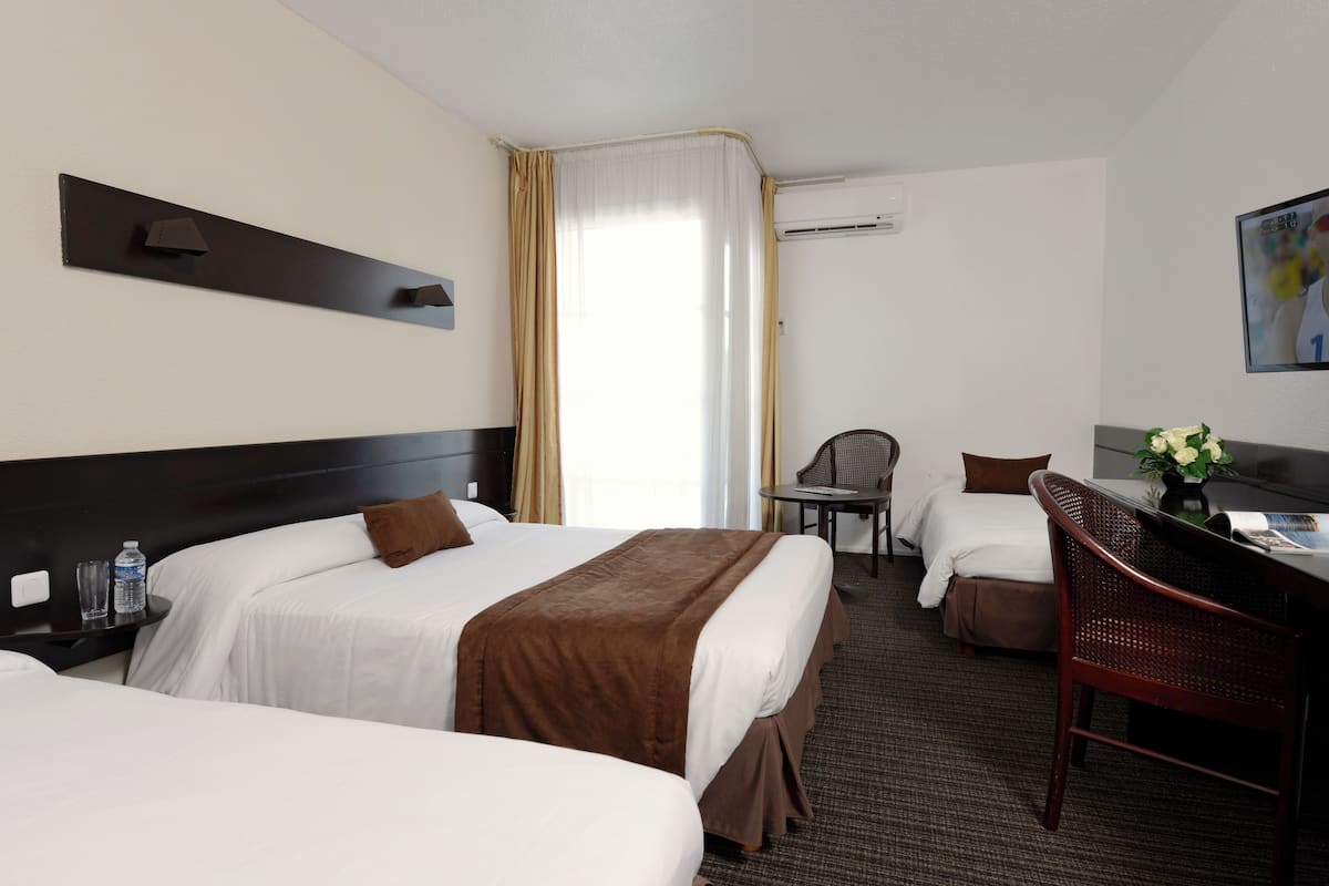 Une chambre d’hôtel avec deux lits, un bureau, une chaise et un téléviseur.