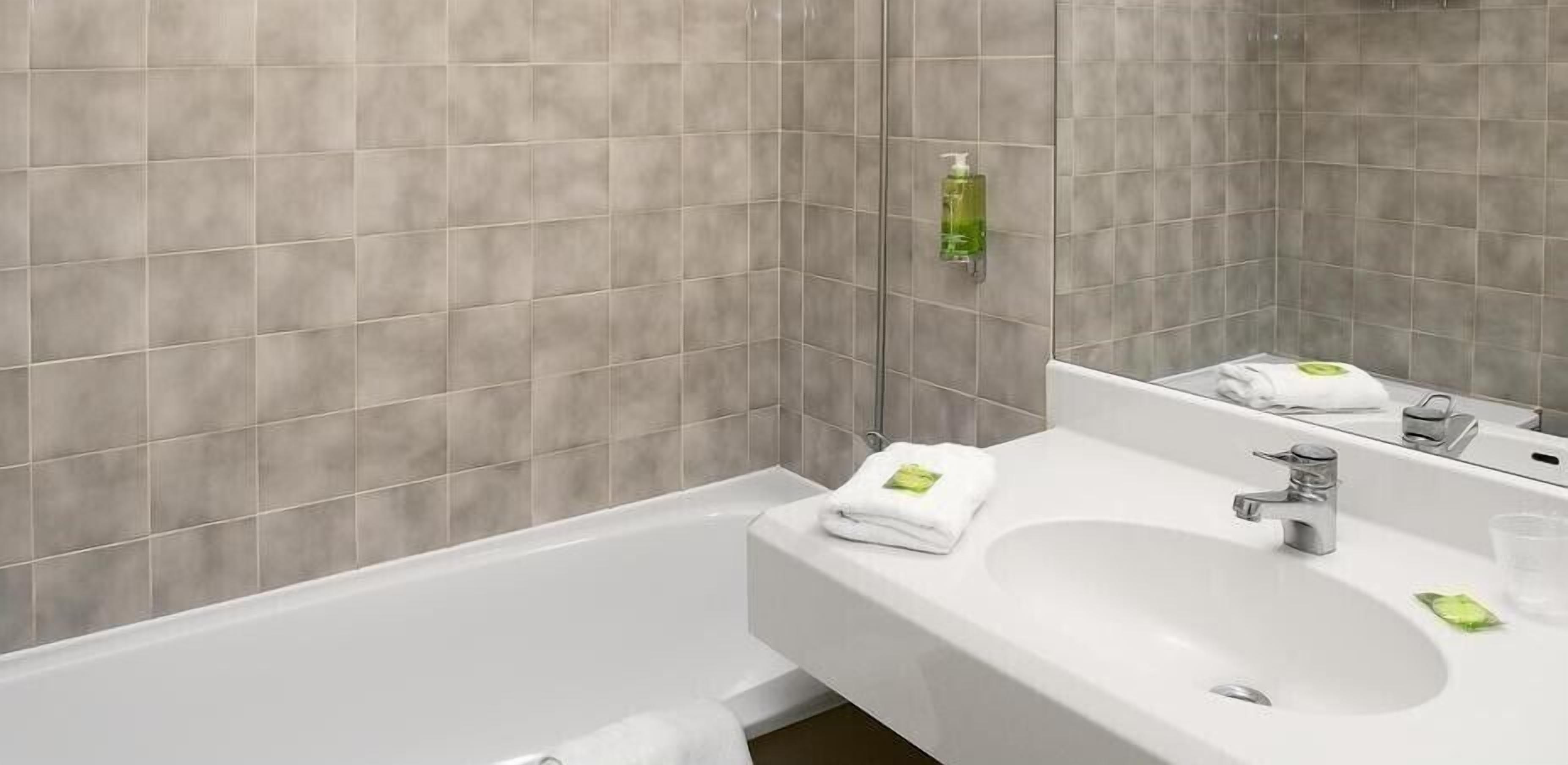 A bathroom with a white sink, mirror, and a green soap dispenser.