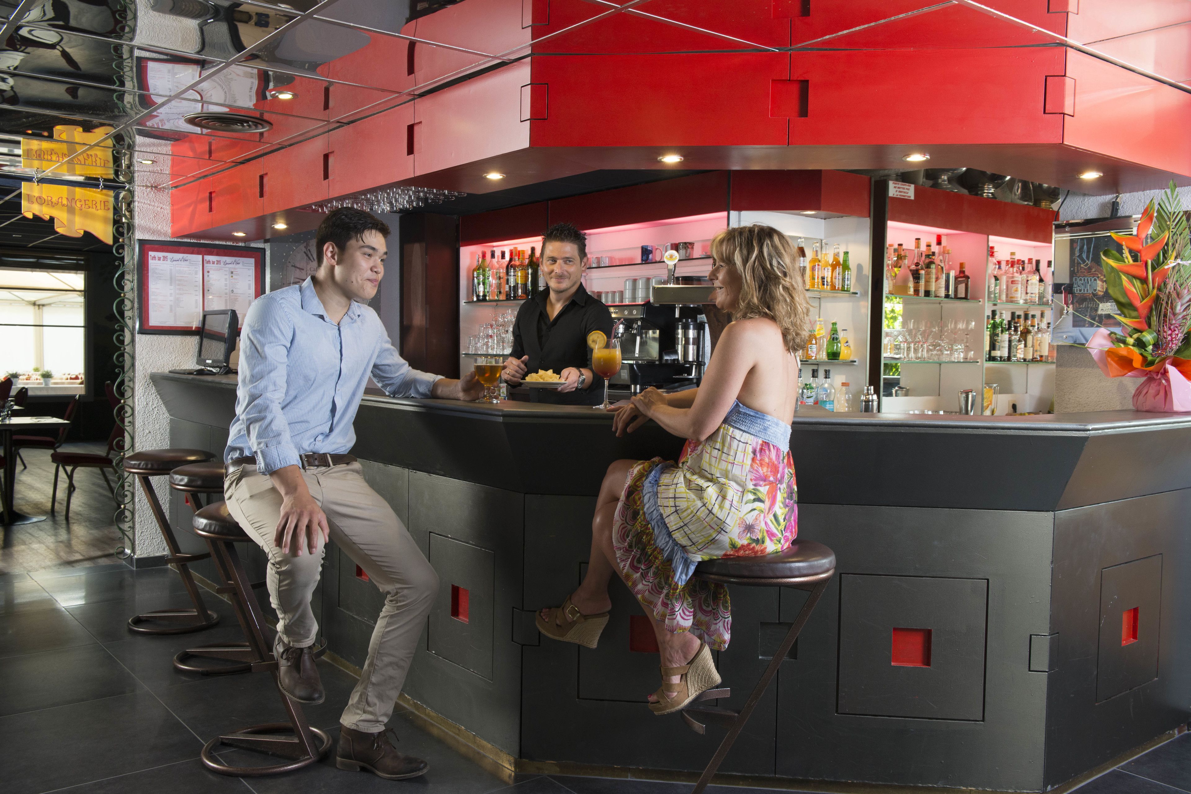 Un espace bar avec des tabourets, un comptoir et un barman.