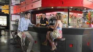 A bar area with stools, a counter, and a bartender.
