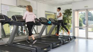 A gym with treadmills, a large mirror, and a potted plant.