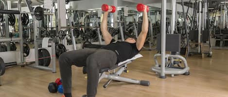 Un gimnasio con diversos equipos de ejercicio, incluyendo mancuernas y máquinas de pesas.